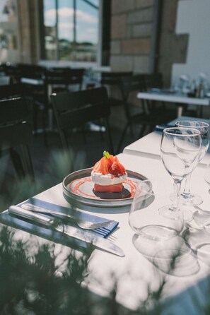 A dining table with a dessert, a wine glass, and cutlery.