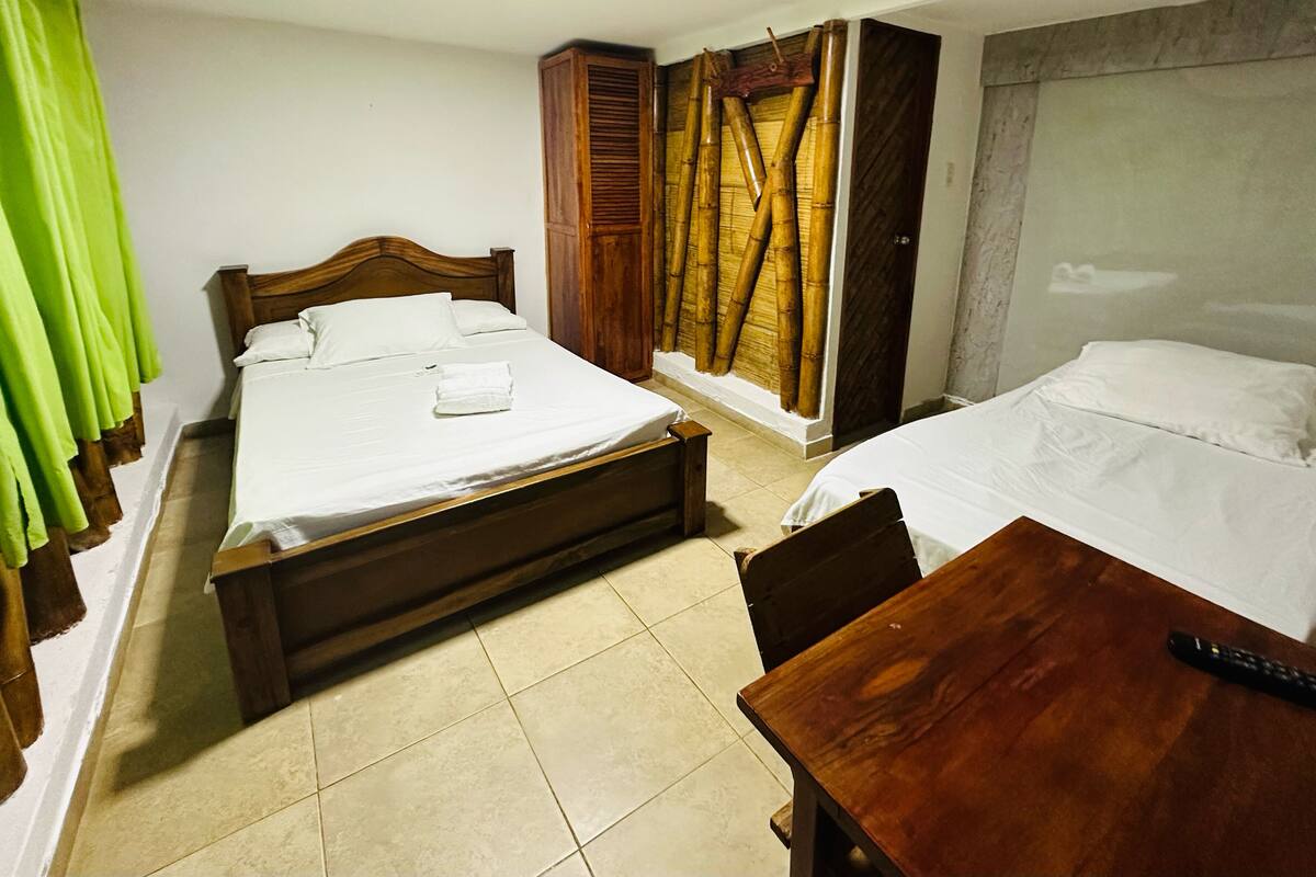 Ein Hotelzimmer mit zwei Betten, einem Holztisch und einem Kleiderschrank.