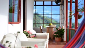 A cozy patio with a white sofa, a small table, and potted plants.
