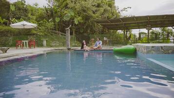 Relax by the serene pool surrounded by lush greenery and shaded seating.