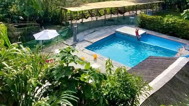 A pool area with a covered seating area and a view of the surrounding landscape.