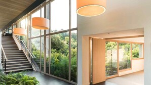 Un interior moderno con una escalera que lleva a un balcón, ventanas amplias y un diseño minimalista.