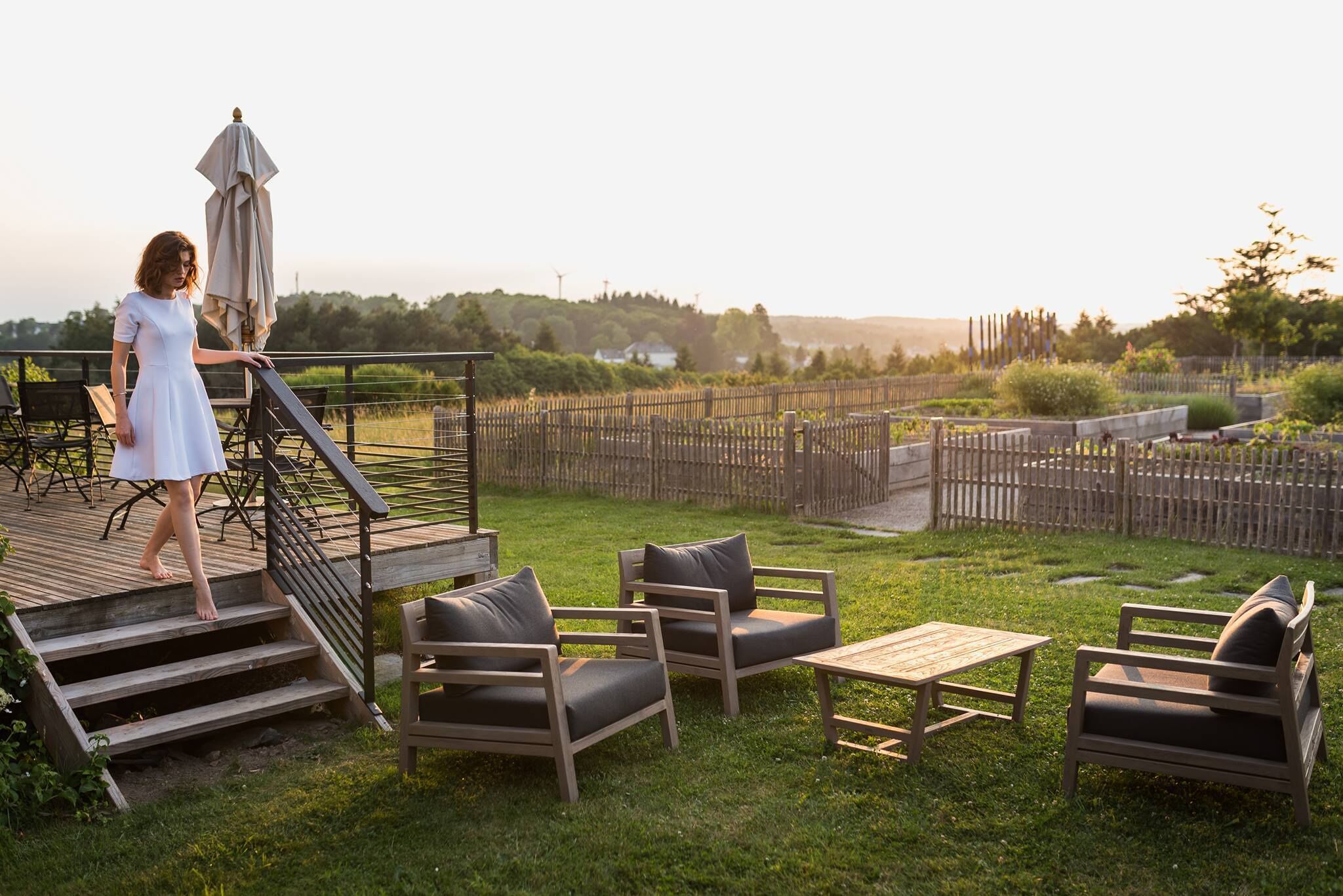 Un patio con mobiliario exterior, una terraza de madera y vistas a un viñedo.