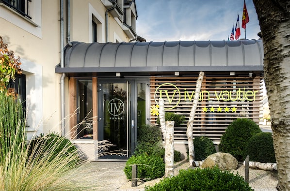 A building with a modern facade, a glass entrance, and a sign with a logo and text.