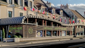Un restaurante de diseño moderno, con techo curvo y varias banderas visibles en el exterior.