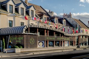 A restaurant with a modern design, featuring a curved roof and multiple flags displayed outside.