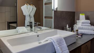 A modern bathroom with a large white sink, a mirror, and a towel rack.