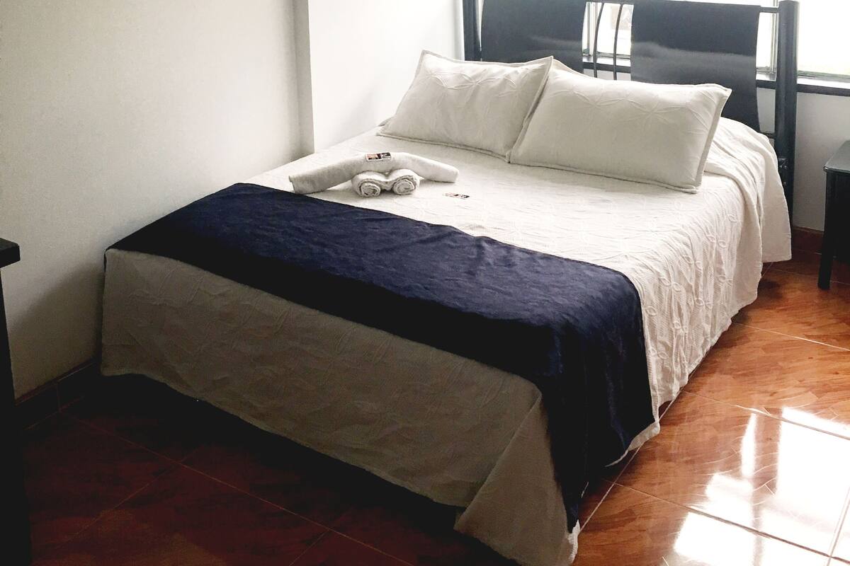 Quarto com cama, janela e pintura na parede.