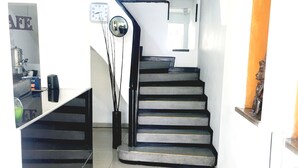 Eine Treppe führt zu einer zweiten Etage, mit einem Geländer auf der rechten Seite und einem Spiegel darüber an der Wand.