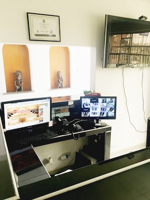 A computer desk with multiple monitors, a telephone, and a framed certificate on the wall. - Casa Paulina (Bogotá)