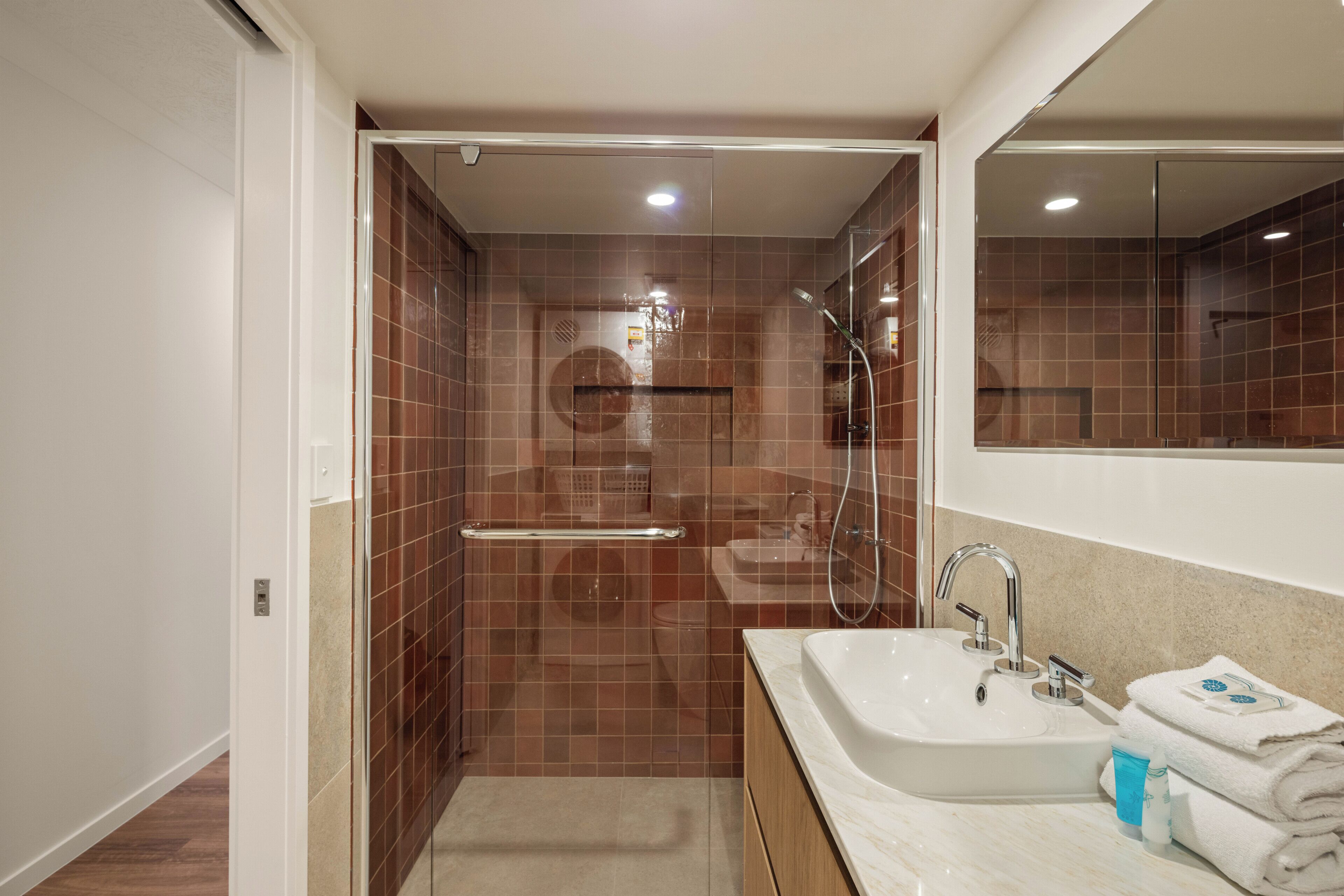 Ein modernes Badezimmer mit Dusche, Waschbecken und Spiegel.