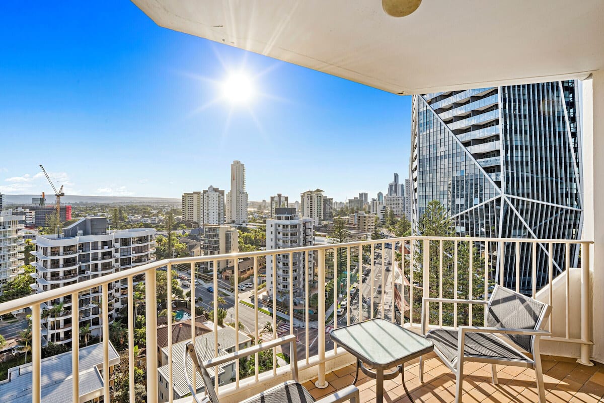 A balcony with a view of a cityscape, including high-rise buildings and a construction crane.
