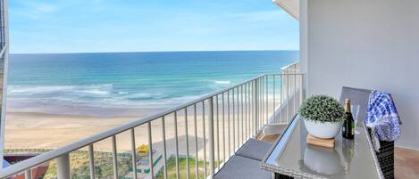 A balcony with a view of the beach and ocean.