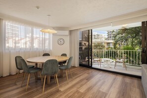 A modern dining area with a round table, chairs, and a clock on the wall. - Breakers North Absolute Beachfront Apartments (Surfers Paradise)