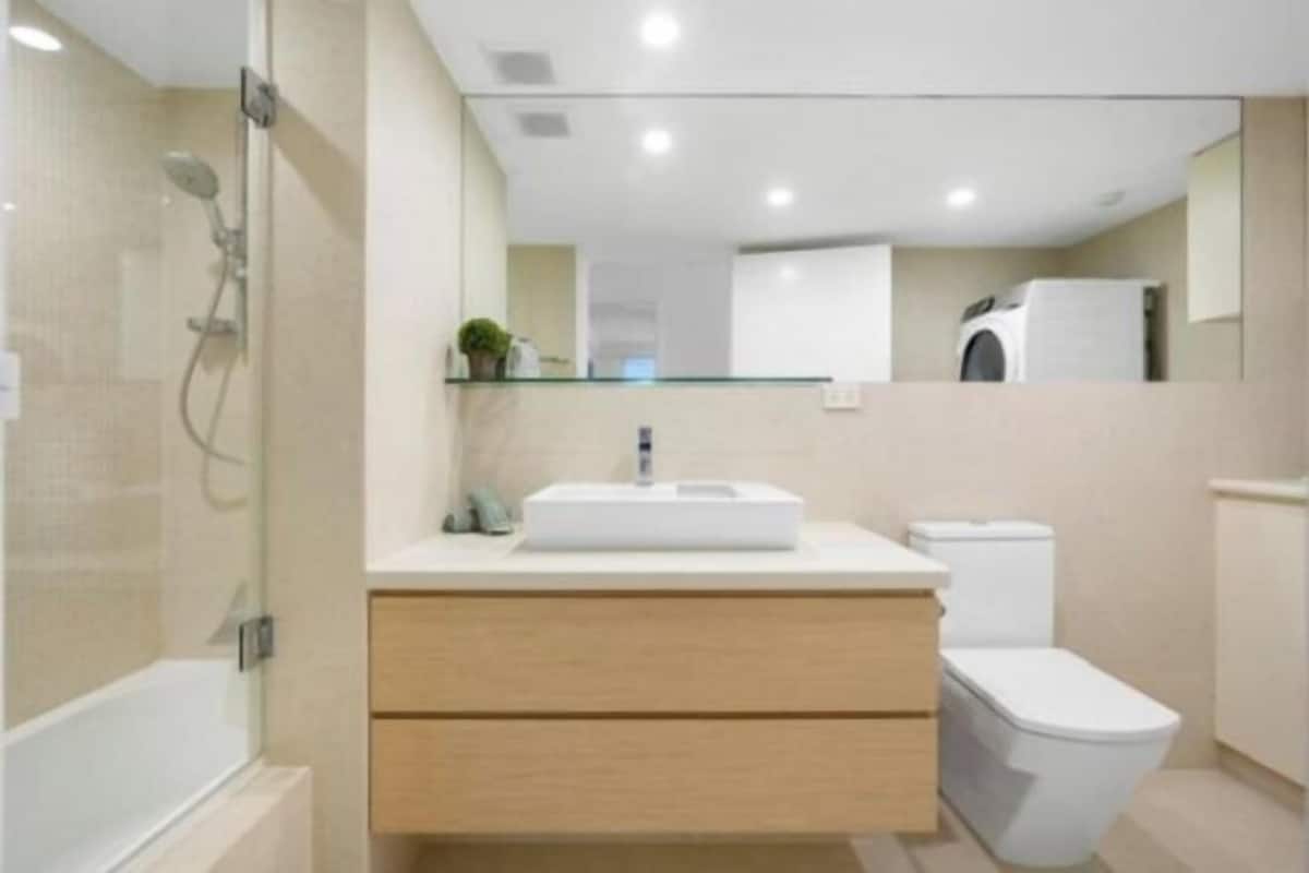 A modern bathroom with a glass shower enclosure, a white sink, and a toilet.
