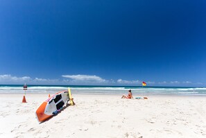 A beach with a lifeguard stand, a lifeguard chair, and a flag. - Breakers North Absolute Beachfront Apartments (Surfers Paradise)