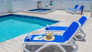 Ein Poolbereich mit Liegestühlen und einem Whirlpool.