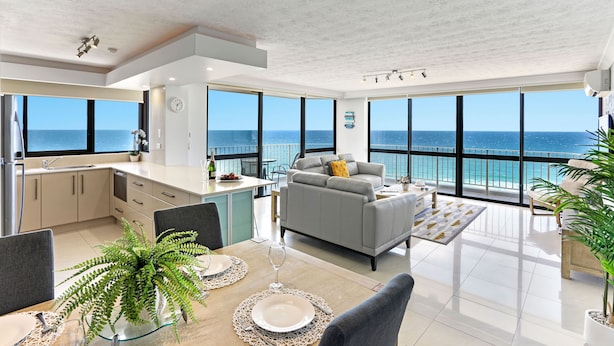 Ein moderner Wohnraum mit Küche, Essbereich und einem Balkon mit Meerblick.