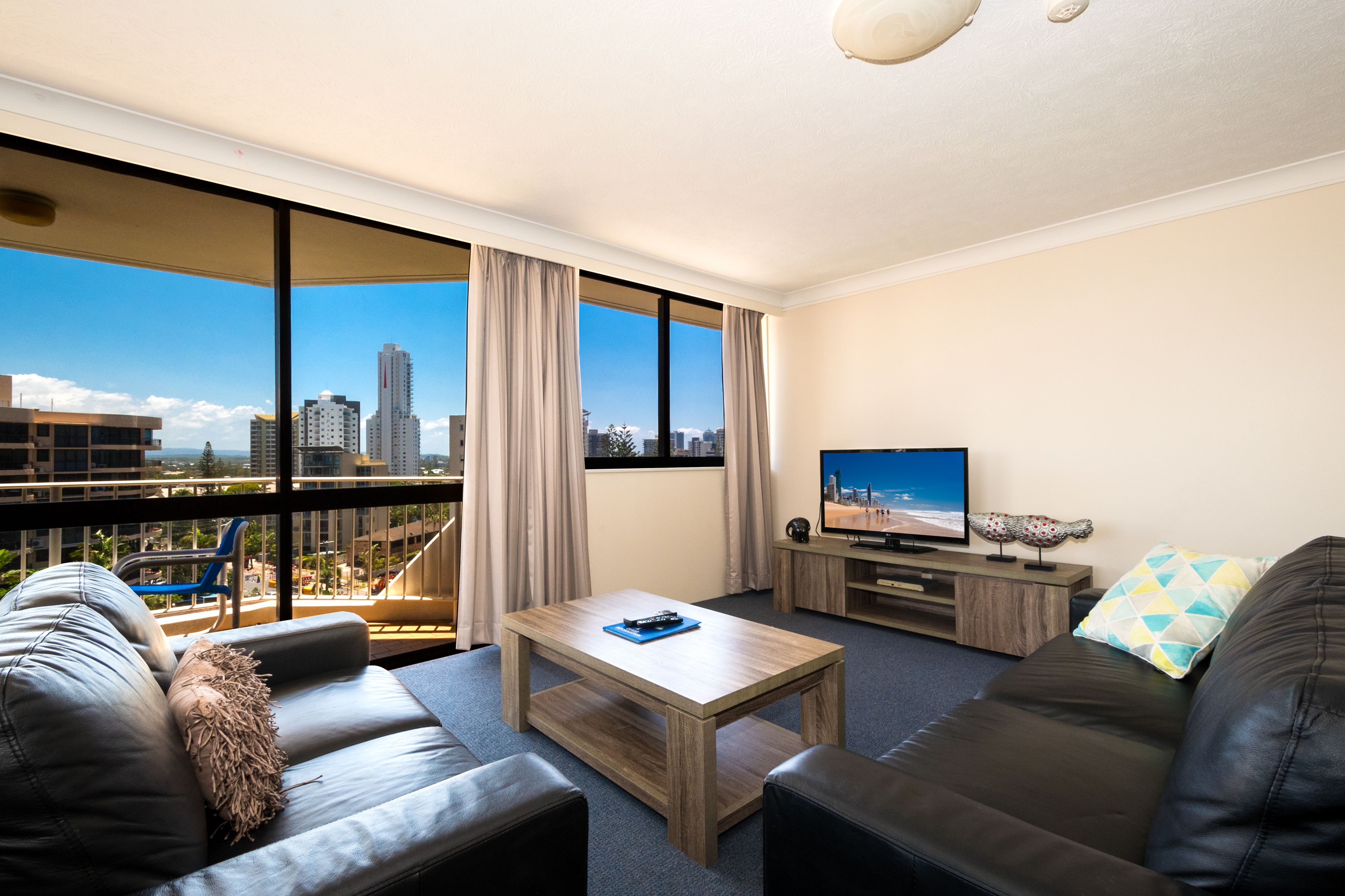 Una sala moderna con vista a la ciudad, un sofá, una mesa de centro y un televisor.