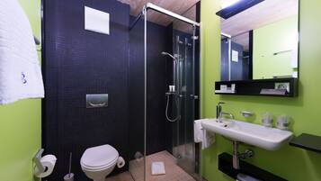 A modern bathroom with a glass-enclosed shower, a white sink, and a toilet.