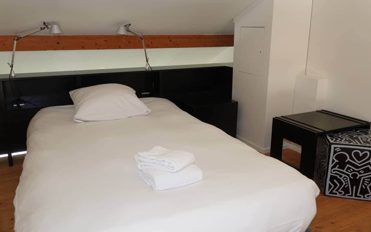 A neatly made bed with white linens, a bedside table with a patterned tray, and a headboard with built-in lighting.