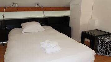 A neatly made bed with white linens, a bedside table with a patterned tray, and a headboard with built-in lighting.