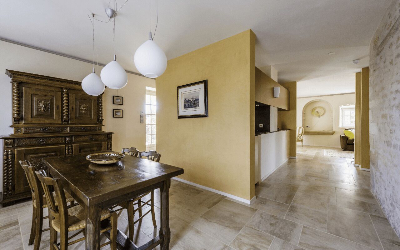 A dining area with a wooden table and chairs, a chandelier, and a large cabinet.