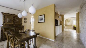 A dining area with a wooden table and chairs, a chandelier, and a large cabinet.