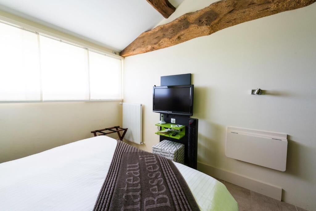 A bedroom with a bed, a television, a radiator, and a window.
