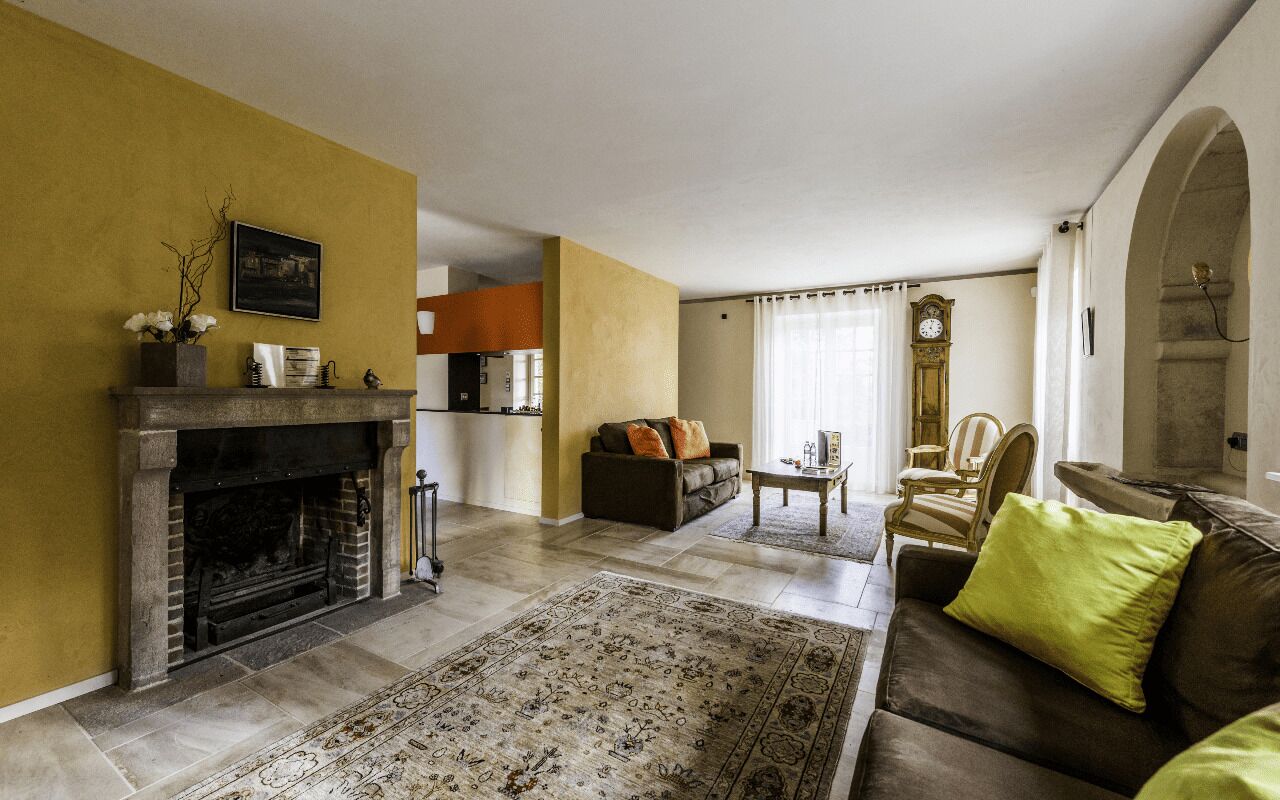 Un salon avec une cheminée, un canapé, une table basse et, au fond, un coin repas.