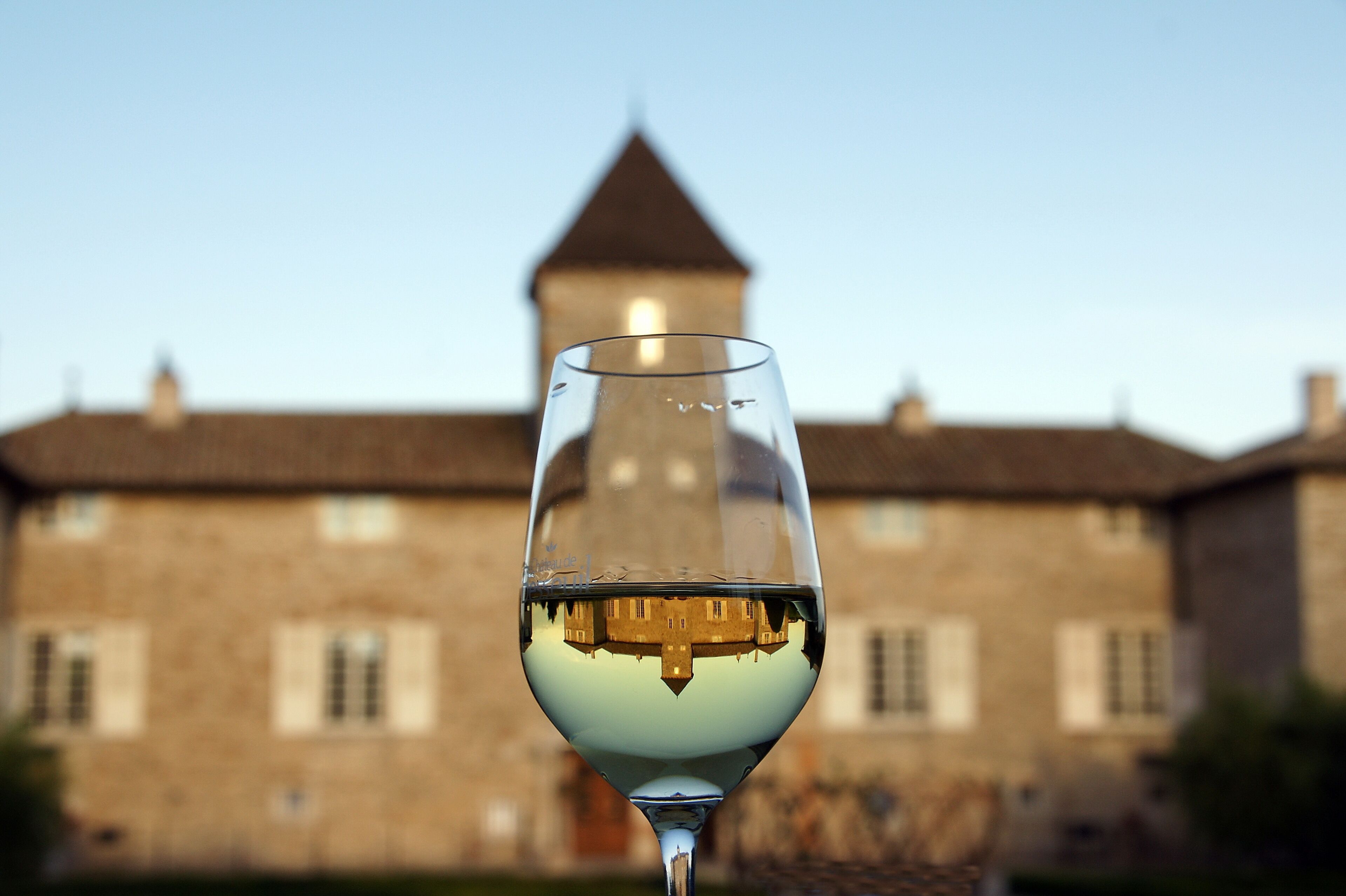 A wine glass with a reflection of a building in the background.