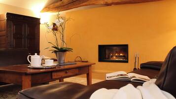 Ein gemütliches Wohnzimmer mit Kamin, Ledersofa, Couchtisch aus Holz und einer Topforchidee.