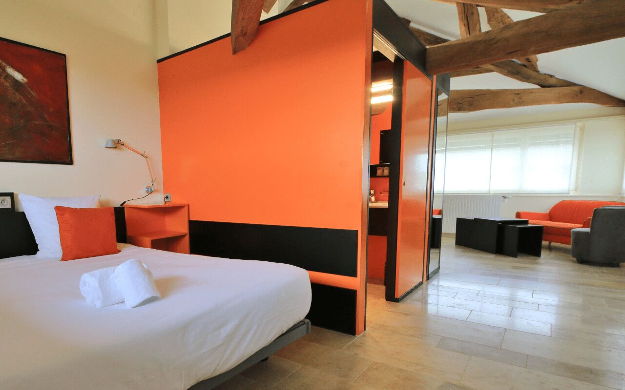 A modern hotel room with a large bed, a desk, and a seating area.