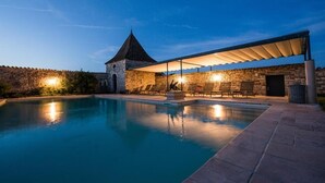 Una piscina con un muro de piedra y una zona de estar cubierta.