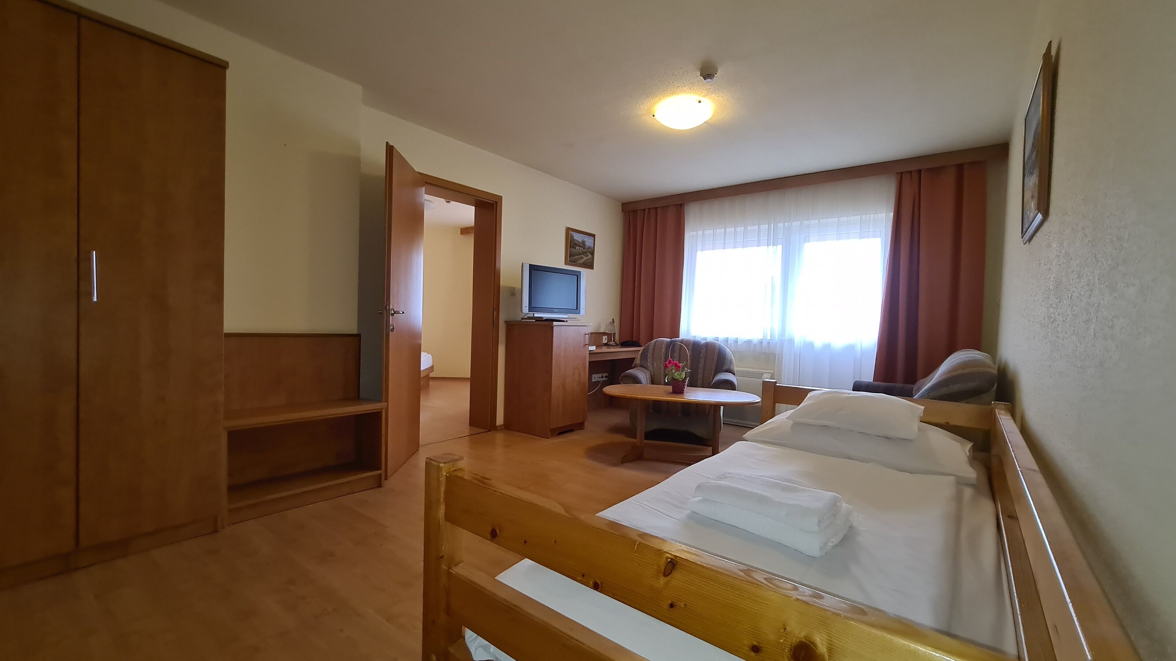 Una habitación de hotel con cama, escritorio con computadora, televisor y armario.