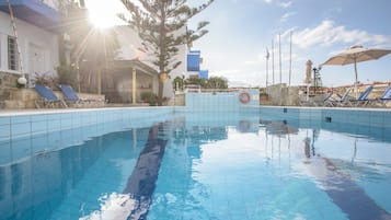 Una piscina al aire libre, sillones reclinables de piscina