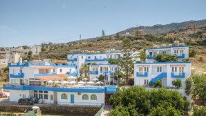 A coastal hotel with multiple blue and white buildings, a swimming pool, and a hillside backdrop. - Belvedere Village (Malevizi)