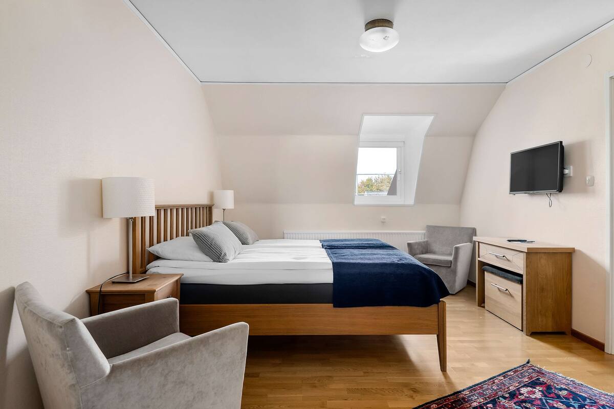 Een moderne slaapkamer met een hoogslaper, een bureau, een televisie en een raam.