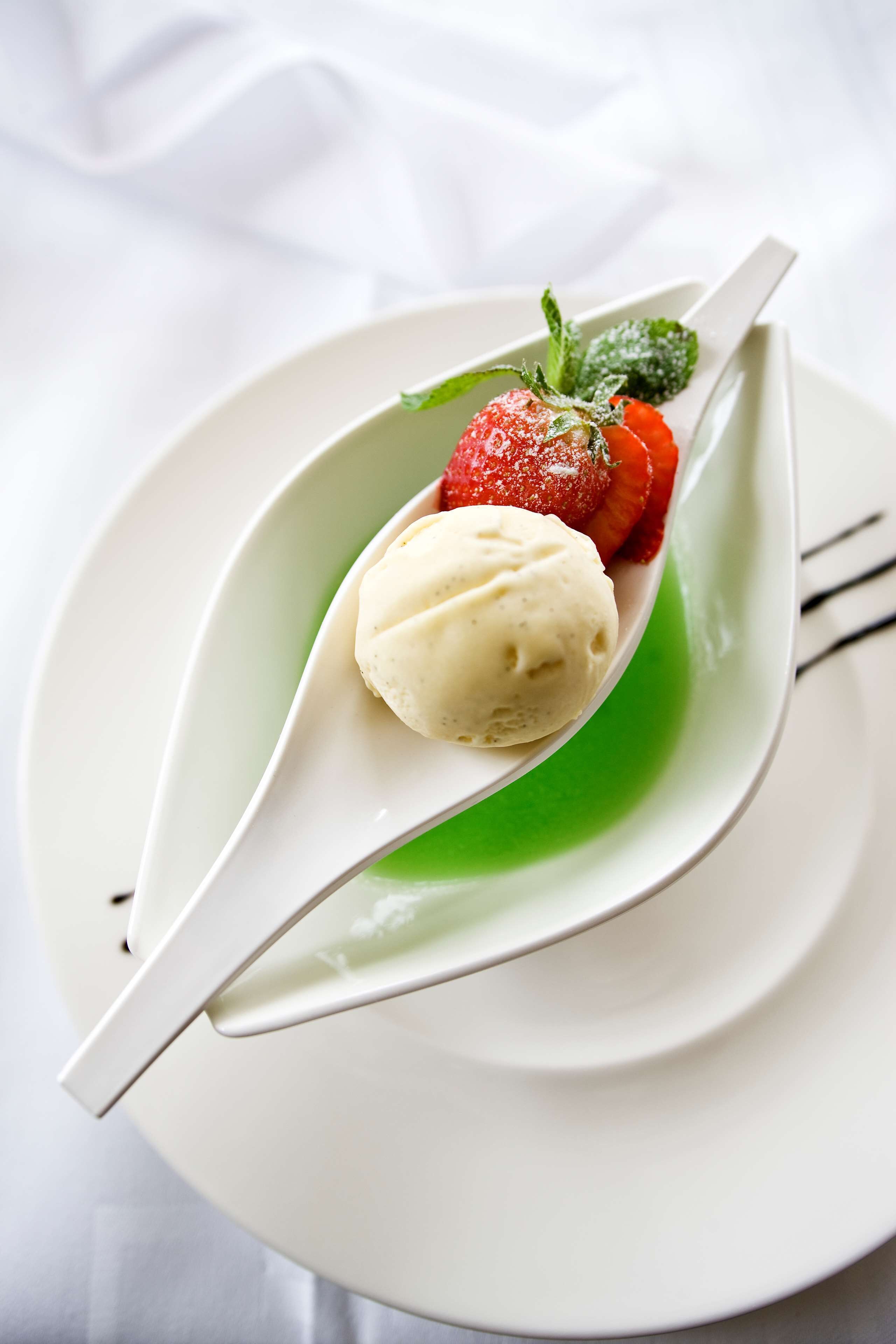 A dessert with a scoop of ice cream and a strawberry on a white plate.