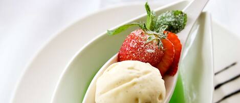 A dessert with a scoop of ice cream and a strawberry on a white plate.