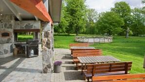 Une terrasse extérieure avec des murs en pierre, des bancs en bois et un espace barbecue.
