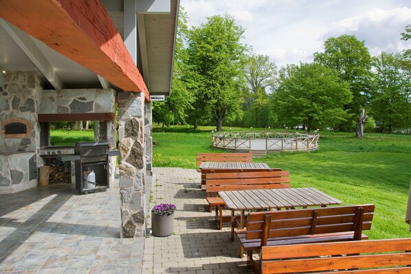 An outdoor patio with stone walls, wooden benches, and a barbecue area.
