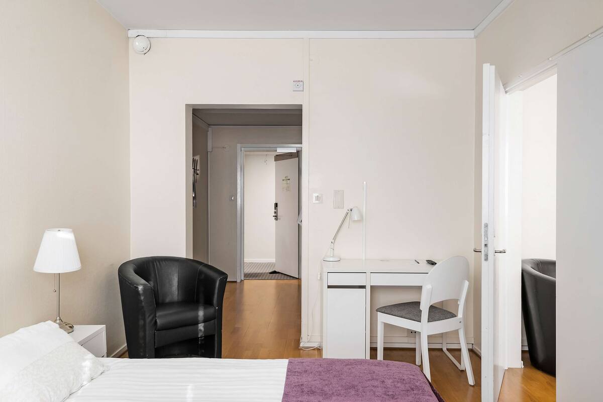 Een hotelkamer met een bed, een bureau, een stoel en een lamp.