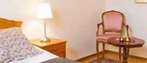 A hotel room with a bed, a nightstand with a lamp, and two chairs.