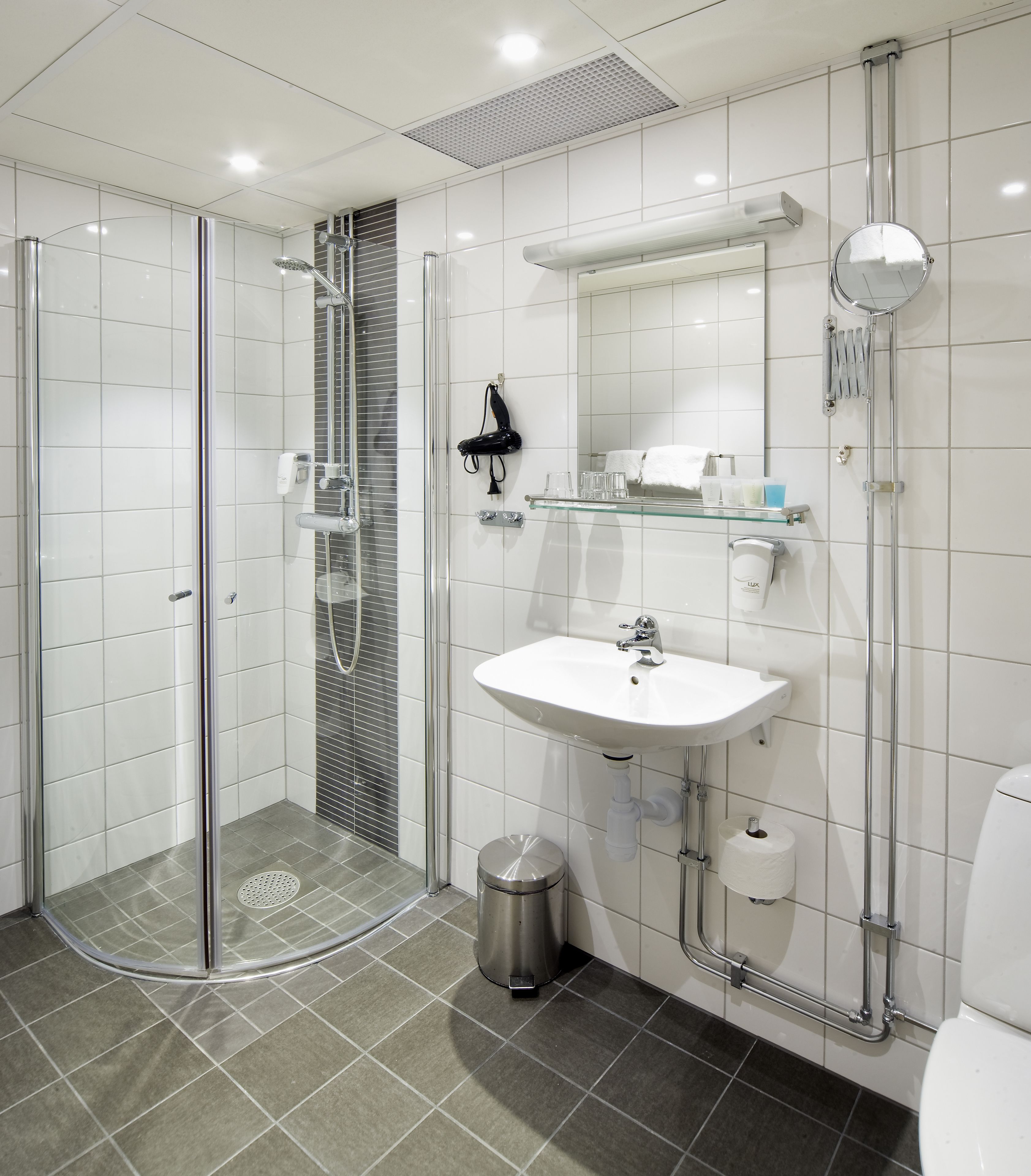 Un baño moderno con ducha de vidrio, lavamanos blanco y un inodoro.