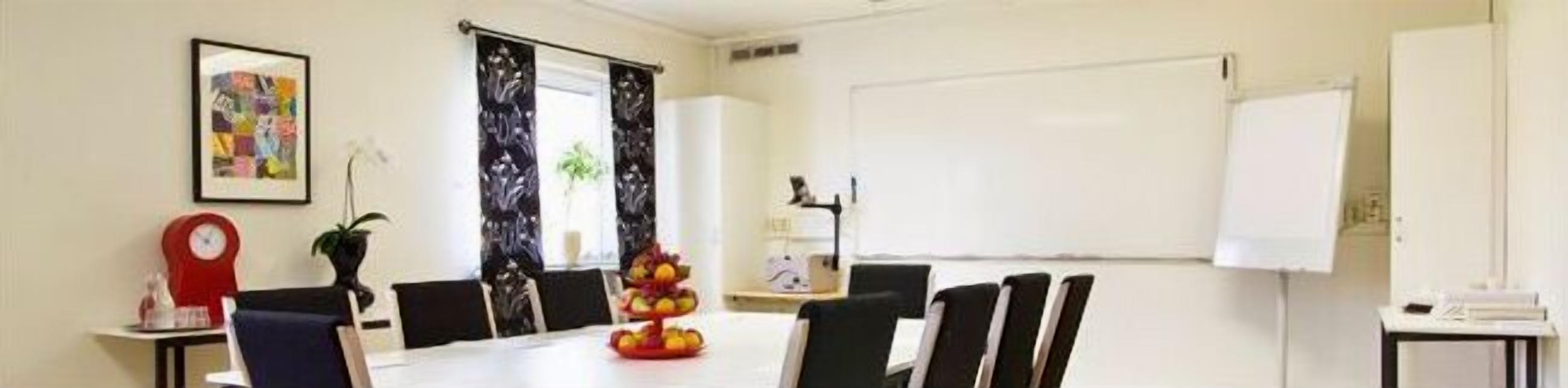 A conference room with a whiteboard, a clock, and a fruit display.