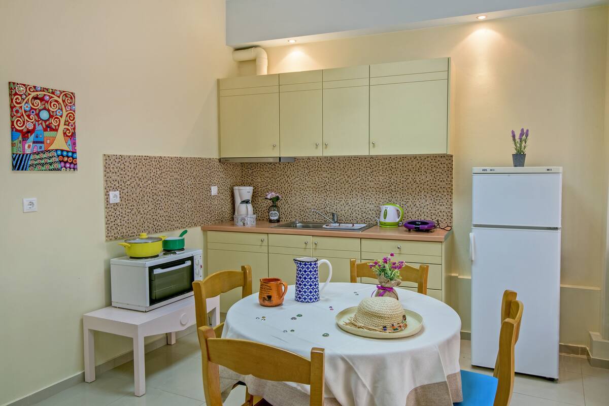 A compact kitchen with a microwave, oven, and sink. There's a small dining table with chairs and a decorative vase.