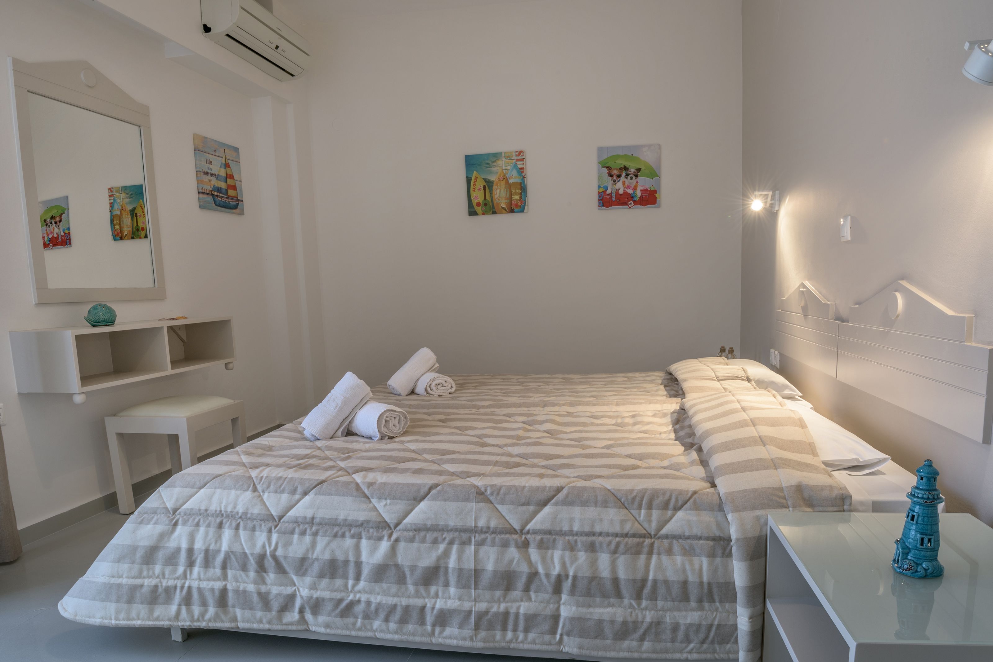 A neatly arranged bedroom with a bed, bedside tables, a mirror, and wall art.