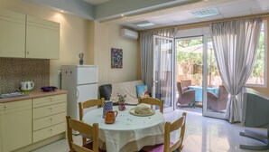 A compact kitchen with a dining area, a refrigerator, a coffee maker, and a table set for four.