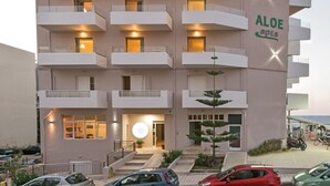 A multi-story building with balconies, a central entrance with a round light, and a sign reading "Aloe apts".
